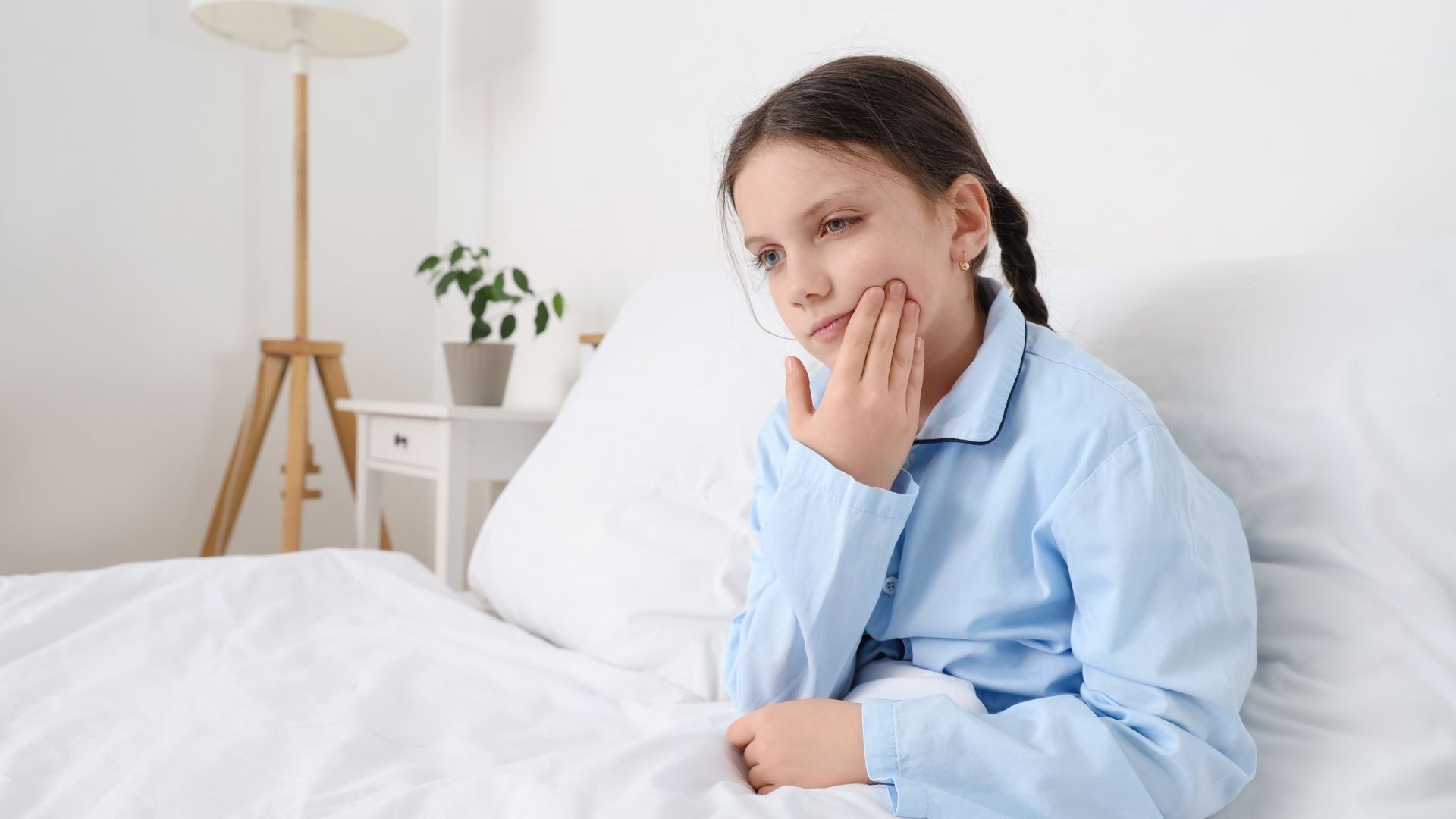 Niña quejándose en la cama por dolor dental
